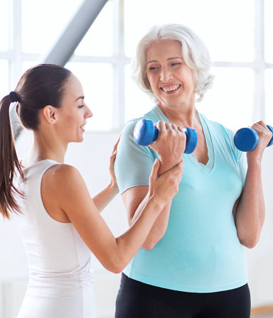 caregiver guiding a senior woman to exercise
